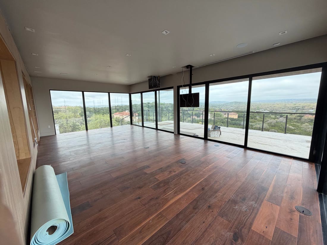 The living room with walnut floors and full height glazing onto the terrace and the hills