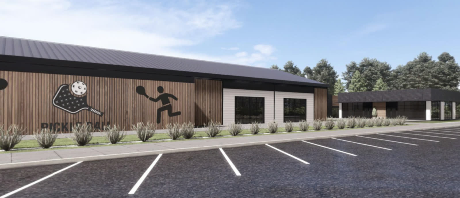 The entry building: a long low block of white brick and vertical timber under a dark roof, with player silhouettes on the wall and cars in the lot in front