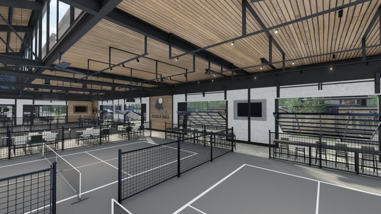 An indoor court seen through the black fence, a screen on the end wall
