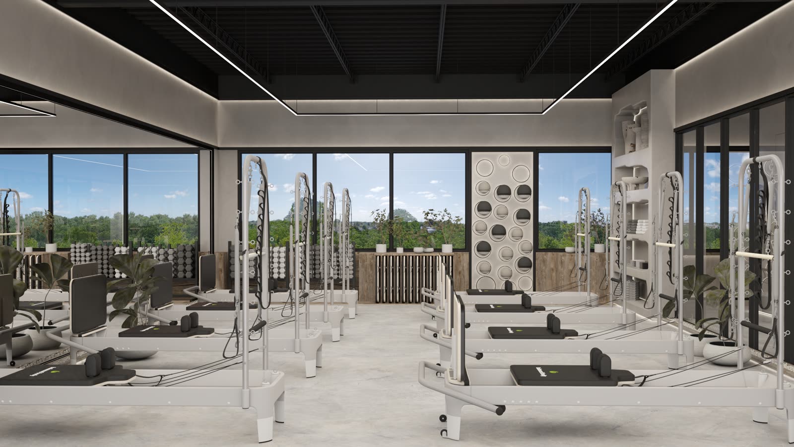 Form Flow Pilates: the reformer studio under a black ceiling with linear lights, rows of reformers, windows down one side and a wall of round niches