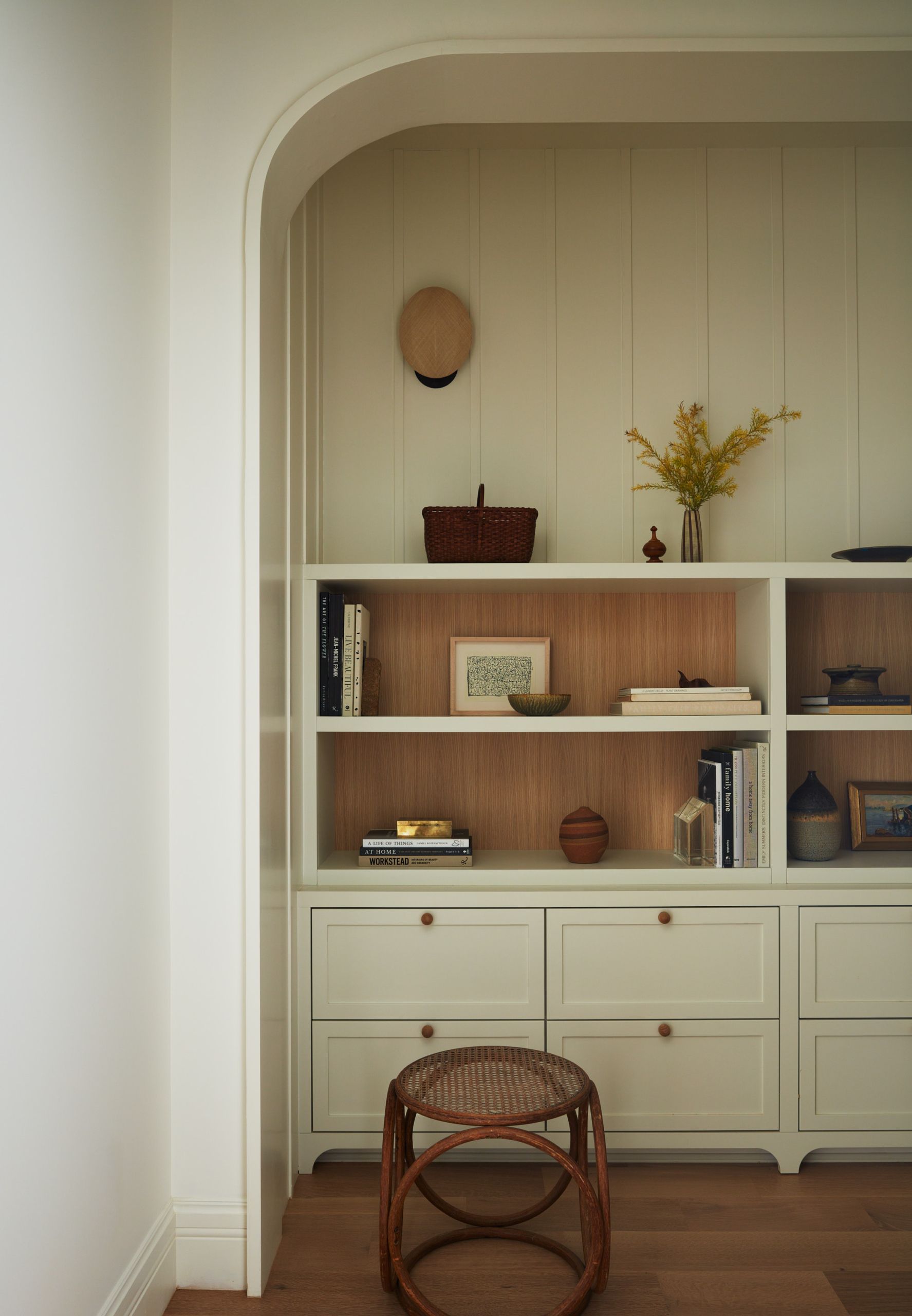 Office or studio, Pale arched niche, timber shelving, cane stool, calm